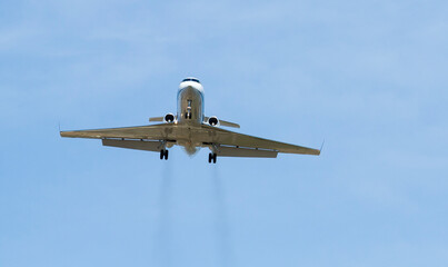Fototapeta na wymiar Private jet on landing approach with vapor trails