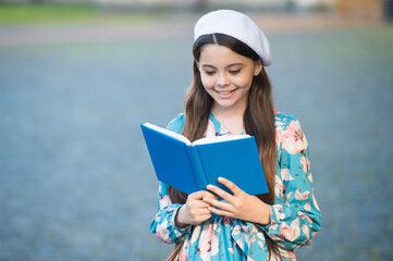 Girl student reading book outdoors, school of good manners concept