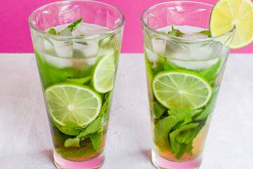Non-alcoholic cold mojito in two glass glasses. Lemonade with lime and mint on a light background