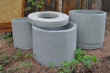 Concrete rings lie on the ground. Preparation for the construction of a well.