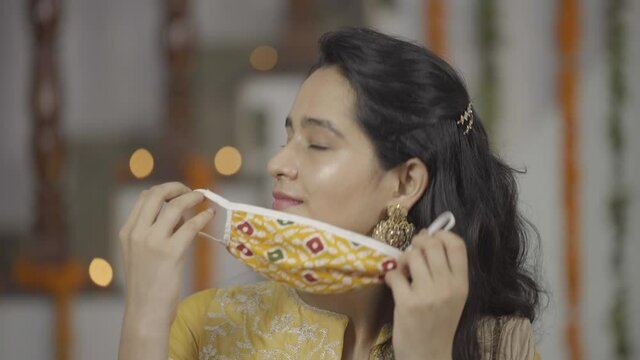 Indian girl in Indian ethnic attire removing Coronavirus protection mask,relax, getting ready for Indian Festival- Raksha Bandhan, enjoying.