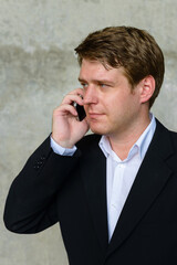 Portrait of young handsome businessman against concrete wall