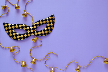 Mask and beads with bells on a purple background on the left side