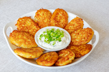 Draniki, hash browns or potato pancakes served with fresh cream and green onions 