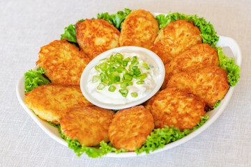Draniki, hash browns or potato pancakes served with fresh cream and green onions 