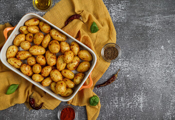 Young potatoes in a dish
Young spiced potatoes in a porcelain dish on the left, on a stone background with space for text on the right, close-up top view.