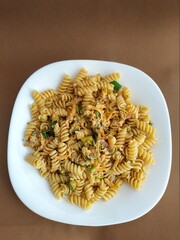 
pasta with vegetables on a plate with a brown background