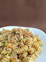 
pasta with vegetables on a plate with a brown background