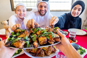 Arabic muslim family being picking chicken from plate being serv