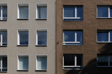 Outdoor sunny exterior front view, typical facade of modern residence or apartment in city of Europe with rectangular windows and earth tone wall.