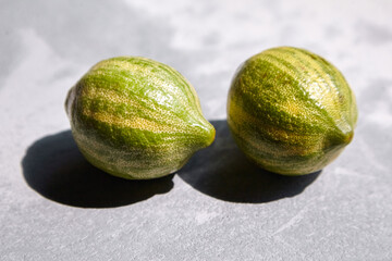 Variegated pink lemons or pink-fleshed Eureka lemons on gray concrete table. Whole citrus fruits with striped rind