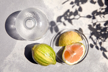 Variegated pink lemon or pink-fleshed Eureka lemon, green-striped rind. Citrus fruit with shadows, Pieces of lemon in transparent glass sauce