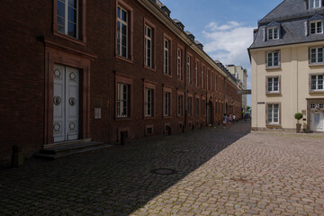 Outdoor sunny street view with walking peoples at narrow alley in front of Stadtmuseum D&uuml;sseldorf, Germany.