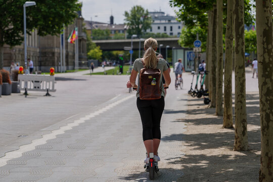 One girl ride E-scooters, trendy urban transportation with Eco friendly sharing  mobility concept, on bicycle lane at promenade riverside of Rhine River in Düsseldorf, Germany.