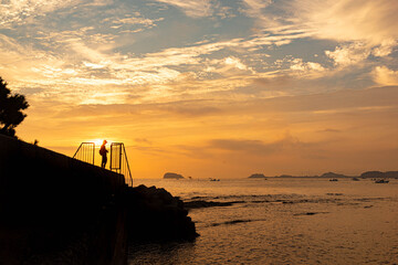 朝焼けの港の風景と釣り人のシルエット