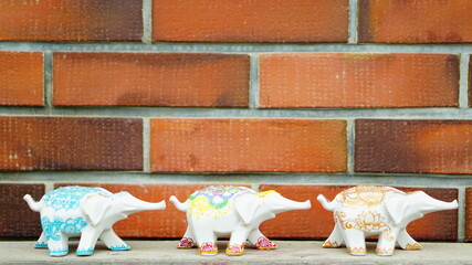 デコレーションされた白い象の置物がレンガの壁の前で並んでいる