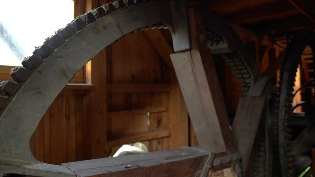 Panning view of massive steel cogwheels inside of vintage watermill.