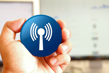 Wlan network icon blue round button holding by hand infront of workspace background