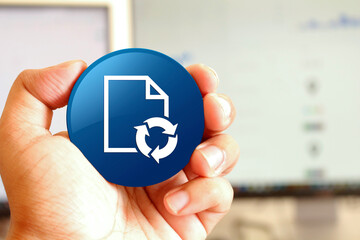Document process icon blue round button holding by hand infront of workspace background