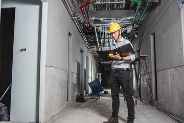 Successful male architect at a building site with arms crossed. Portrait Of Construction Worker On Building Site. Young serviceman Asians engineering smiling happily in the works ,Engineer concept,