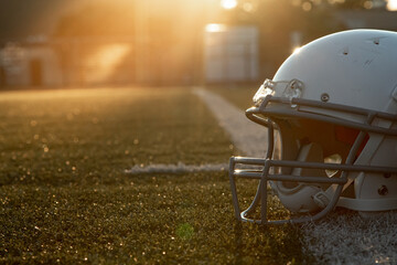 american football helmet on the grass, sports  safety equipment on turf during golden hour