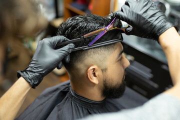 hairdresser's hands cutting hair with scissors to a man