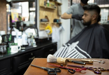 hairdresser with tools and smiling bearded man in the background