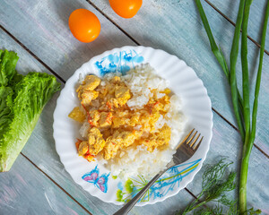 Breakfast with rice and chicken meat and fresh vegetables on a wooden table