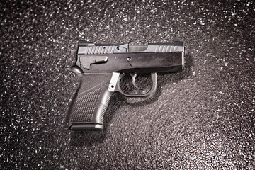 9mm pistol on a metallic background, pointing to the right.