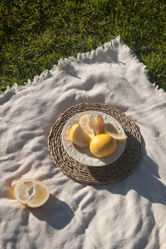 Yellow australian grayfruit cut into pieces in white porcelain vintage plate. The plate staying on the wooden stand. Outdoor.