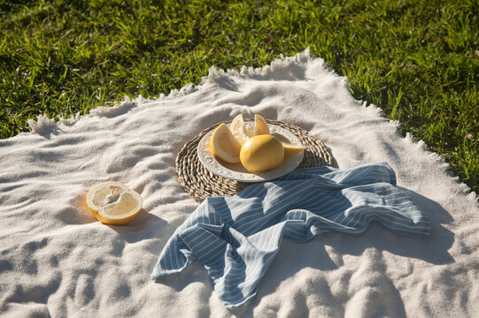Yellow australian grayfruit cut into pieces in white porcelain vintage plate. The plate staying on the wooden stand. Outdoor.