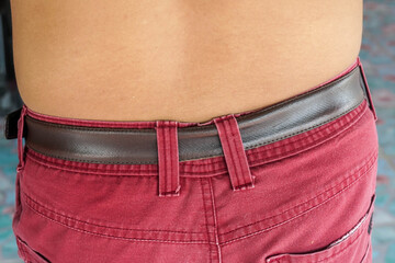 close up back of the man with small belly wearing red pants with belt