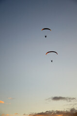 Two Motorized Hang Glider Flying Away in the Evening Sky