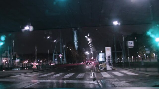 Car travels through night city streets in the rain