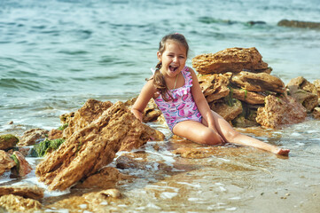 A happy little girl is resting on the sea coast . Concept of children's health recreation in the fresh air
