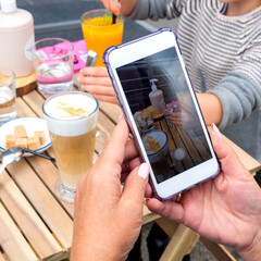 Woman's hands make selfie of a cup of coffee in a street cafe. Photography is needed for social networks.