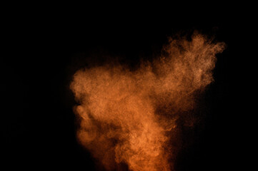 Orange powder explosion on black background. Colored powder cloud. Colorful dust explode. Paint Holi.