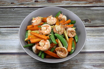 Traditional fried and stirred fresh peeled shrimp, cutting carrot, baby corn and string bean seasoning with pepper on the plate. Famous appetizer menu in Asia restaurant. 