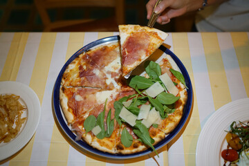 Homemade pizza with prosciutto (Parma ham), rocket leaves and parmesan cheese on table background.