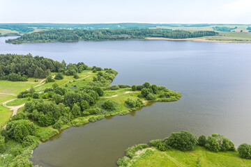 Fototapeta na wymiar blue lake and green forests on a sunny summer day. aerial view from flying drone