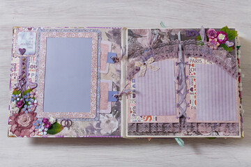 Scrapbooking wedding photoalbum spread with pink and purple paper decorative elements, flowers, beads, tapes, ribbons, hearts and frames for phographs.