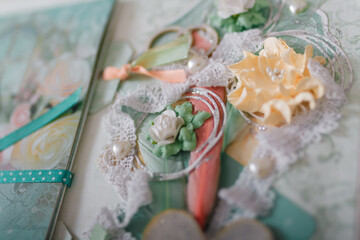 Soft focused close up shot of scrapbooking photo album page with paper decorative elements, flowers, hearts, ribbons, beads. Leisure and hobby concept.