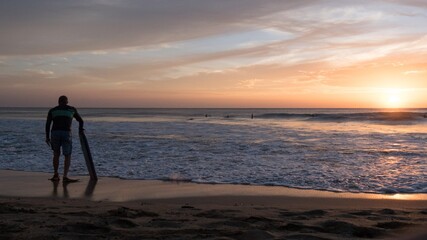 Body boarder standing in front of Playa Grande beach during Sunset. Costa Rica.