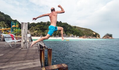 Man jumping from a deck in a paradise island. 