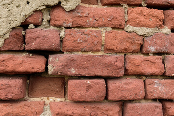 Fototapeta premium Ancient brick wall for a backdrop. Concrete, plaster. Red color. Dispersal, destruction, weathering.