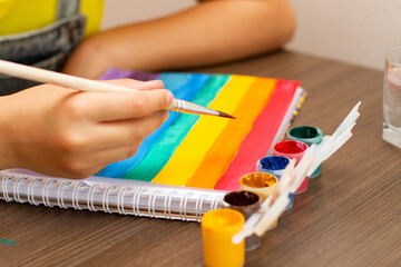 Young African American kid girl drawing or painting rainbow picture