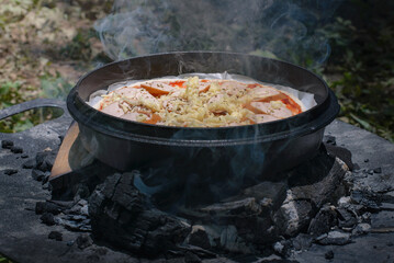 Cooking dinner pizza in camp oven over hot coals in the forest,Outdoor cooking.