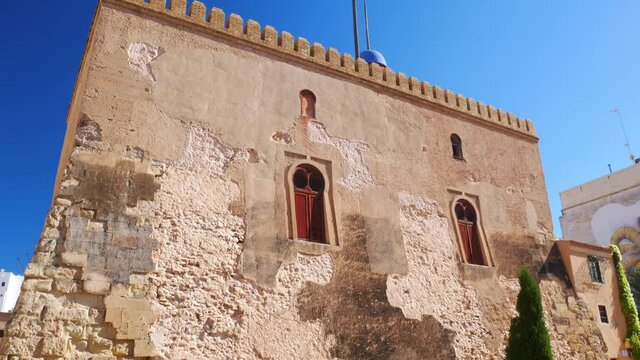 "Calaforra tower". Tilt down shot of an old muslim tower from the XII century with a bystander. Elche, Spain.
