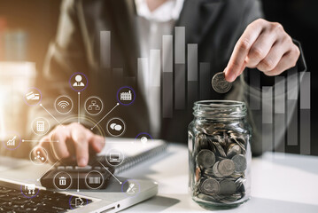 Businesswoman hand puting coins in glass for saving money at home office. concept finance and accounting in the home.