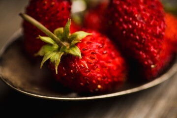 Red ripe wild strawberry in old vintage spoon on the rustic background. Selective focus. Shallow depth of field.
